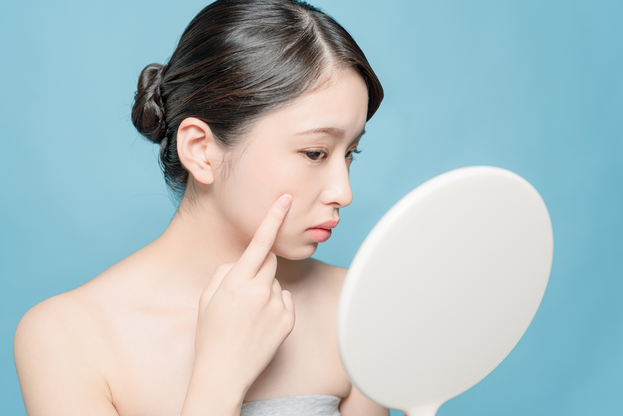 Woman examining dry skin in mirror