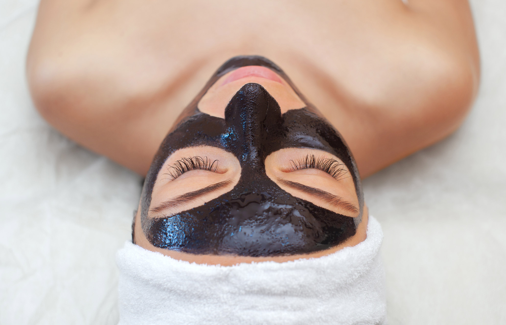 Woman-lying-down-with-a-carbon-mask-before-carbon-facial